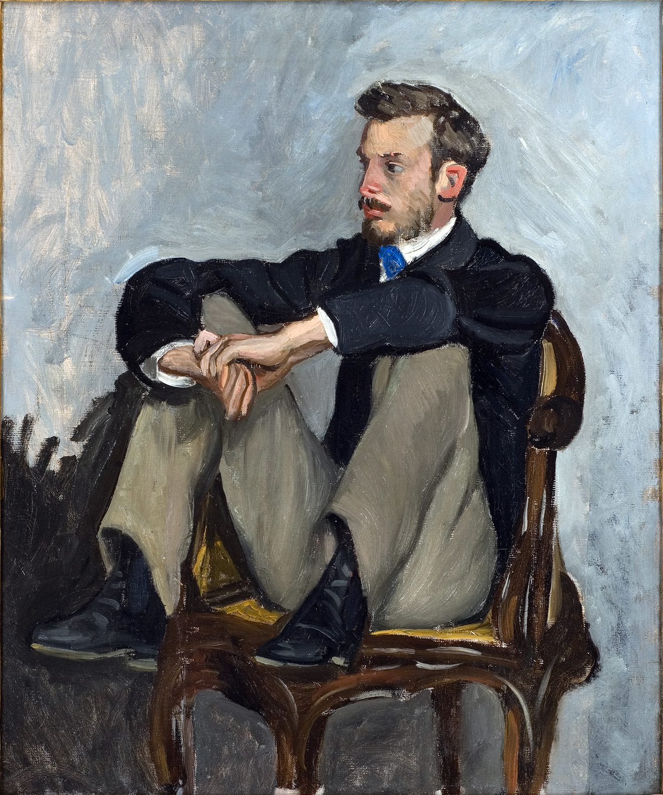 Impressionist oil painting by Frรฉdรฉric Bazille showing Auguste Renoir sitting in a chair with his legs pulled up, highlighting the heavy texture and wide cut of his light brown trousers.